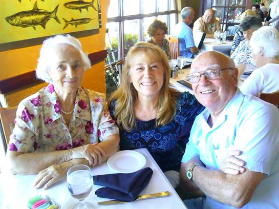 Three people sit together at a restaurant table, sharing smiles and conversation.