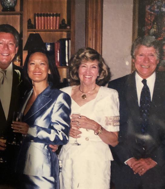 Four friends enjoy drinks and conversation at a stylish event in a well-furnished setting.