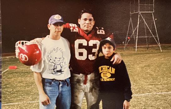 Boys express joy alongside a football player after practice under twilight skies.