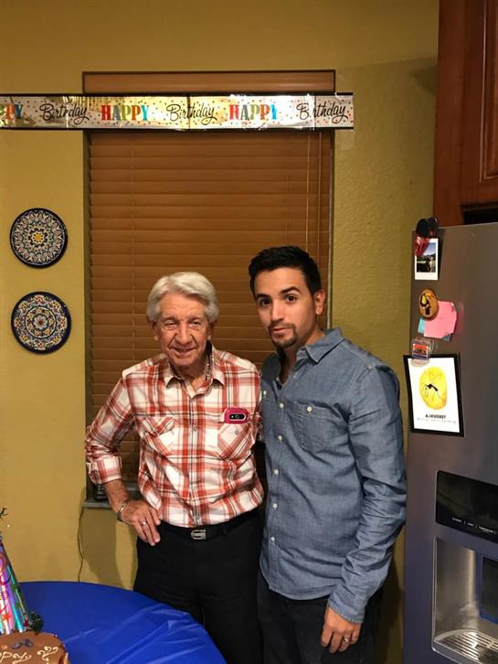 Two men stand together in a warm kitchen adorned with decorations for a celebration.
