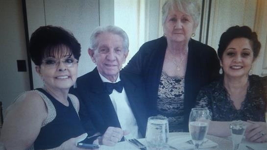 Three people sit at a table, dressed in formal attire, engaged in lively conversation over dinner.