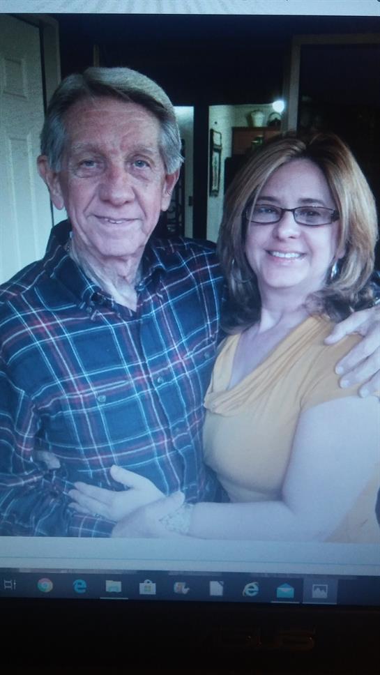 A couple shares smiles and hugs in a warm, family-filled living room.