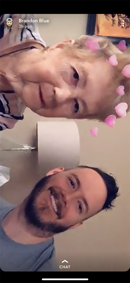 A young man and an elderly woman smile together, enjoying each other's company in a warm atmosphere.