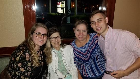 Four friends gather at a cozy restaurant, smiling happily and enjoying their evening together.