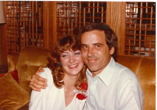 A couple embraces and smiles together in a lively restaurant setting, radiating happiness.