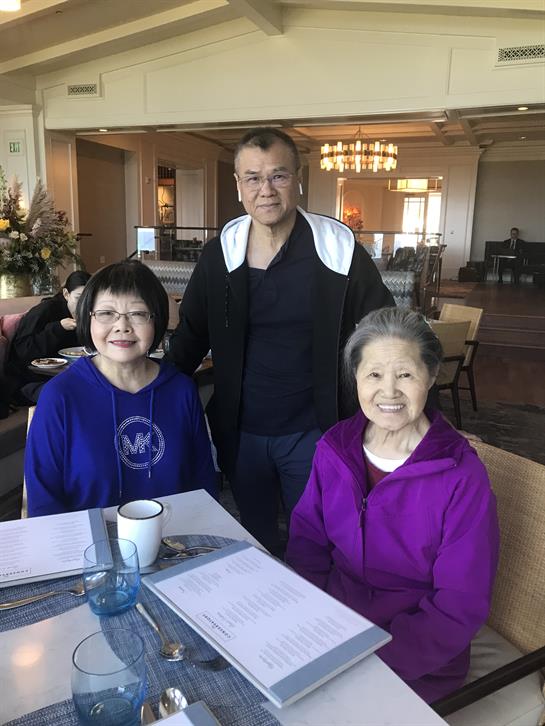 Three people enjoy a meal together at a restaurant, sharing laughter and conversation.