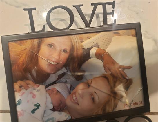 Two women smile while holding a newborn in a warm and welcoming environment.
