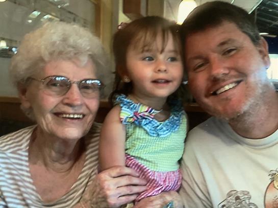 A cheerful moment shows a woman, a girl, and a man enjoying their time together in a casual setting.