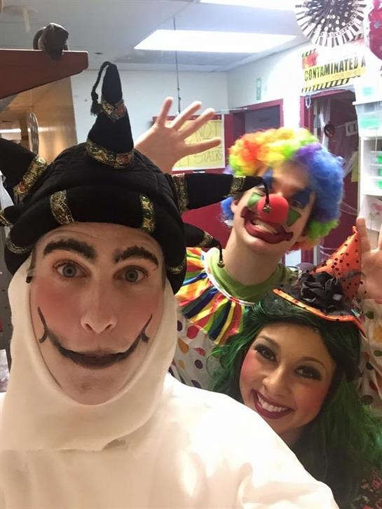 Entertainers wearing costumes smile and pose in a lively atmosphere during a celebration.