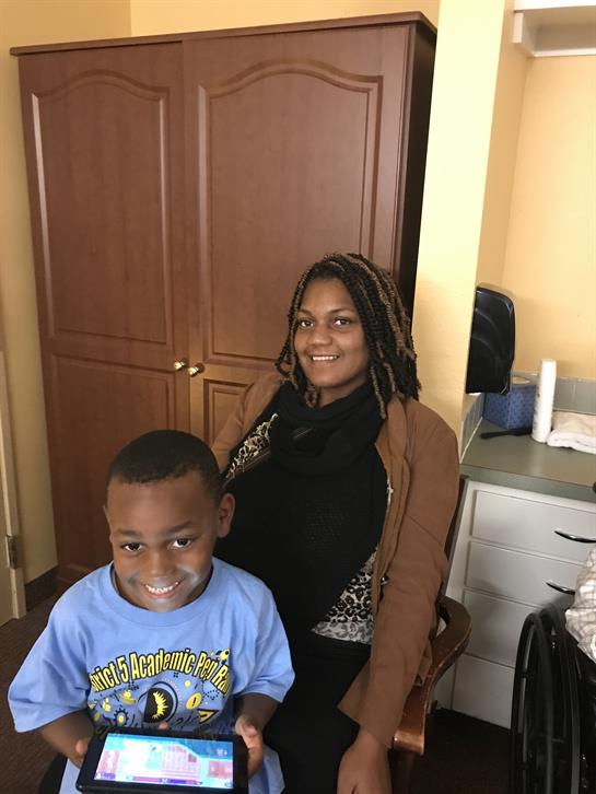 Joyful mother and son smiling while seated in a warm kitchen atmosphere, surrounded by homey decor.