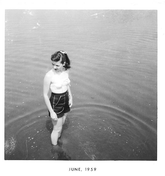 A woman is playfully wading in a lake, enjoying the warm weather on a summer day.