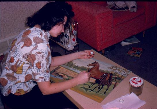 Artist focusing intently on painting horses with vibrant colors in a warm, inviting room.