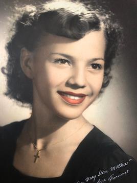 A young woman beams with joy, flaunting her curls and classic style, radiating confidence.