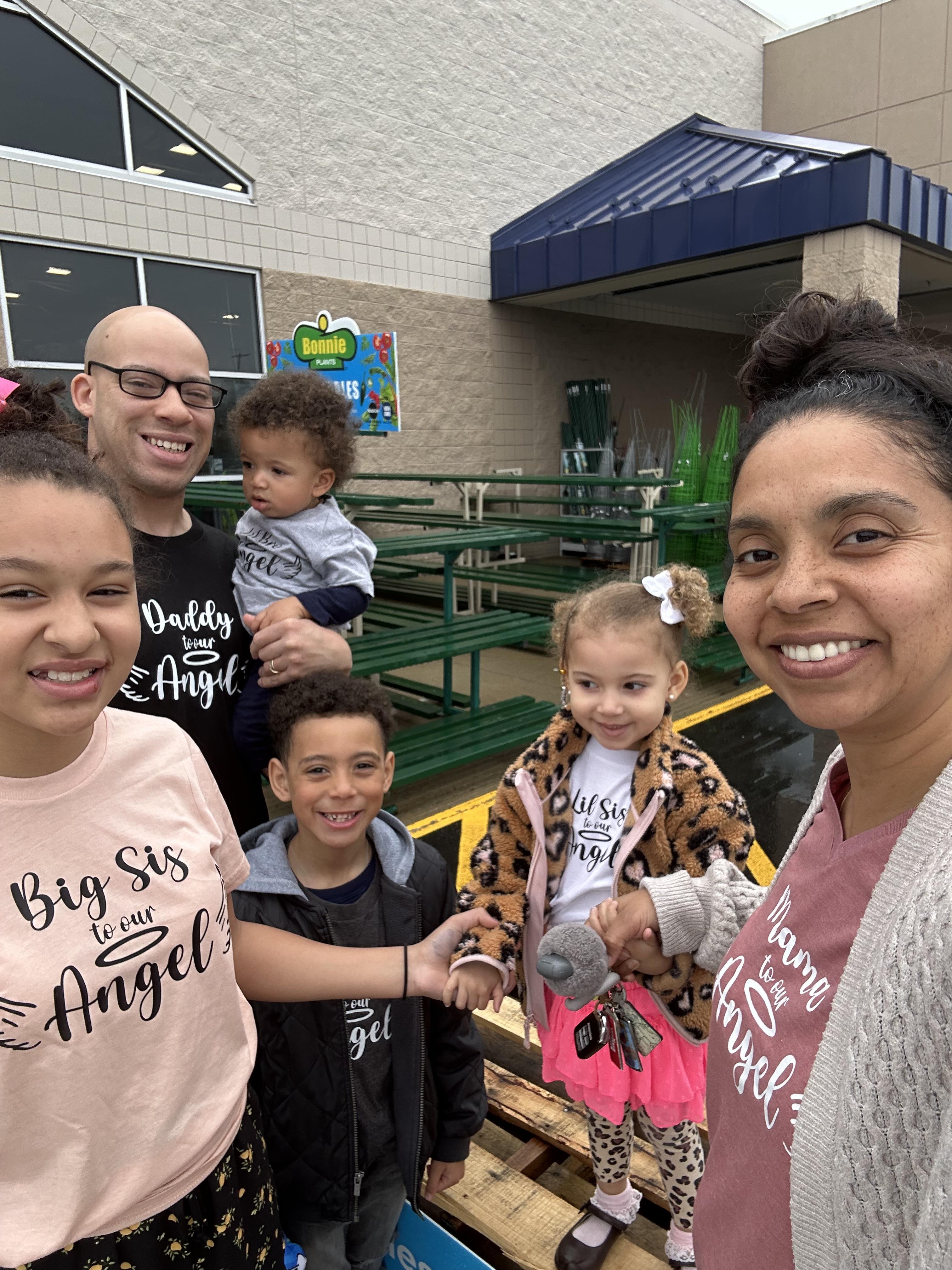 A family is enjoying a day out, posing together outside a store, wearing matching outfits.