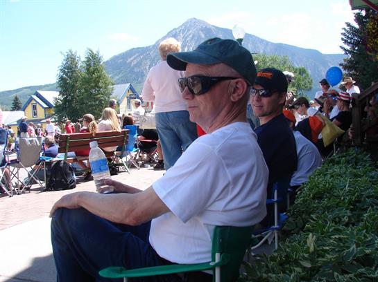 People gather in a sunny outdoor location enjoying a lively event with mountain scenery.