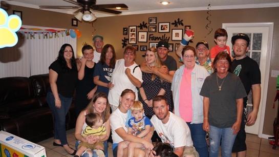 A large group of family members enjoys a vibrant celebration in a cozy living room, filled with joy.