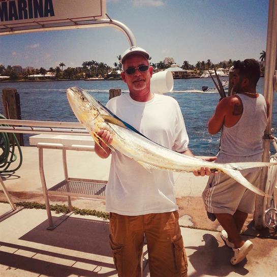 Two fishermen enjoy a successful day at the marina while holding a large fish