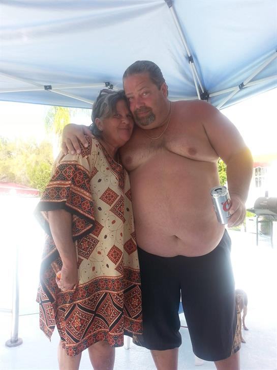 Two people share a joyful moment under a blue tent in a cheerful outdoor gathering.