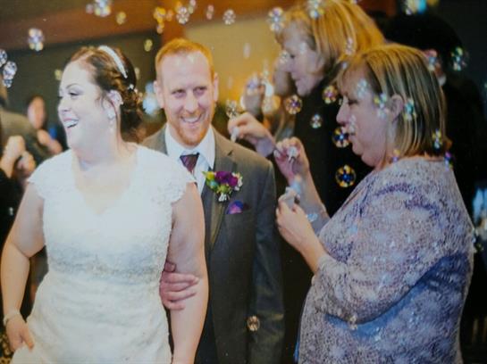 A joyful couple enjoys their wedding reception surrounded by family and friends creating bubbles.