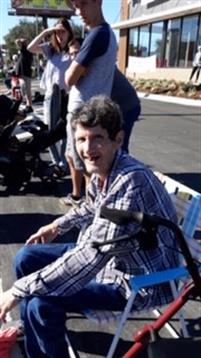 People are gathered outside on a sunny day, engaging in various activities and conversations.