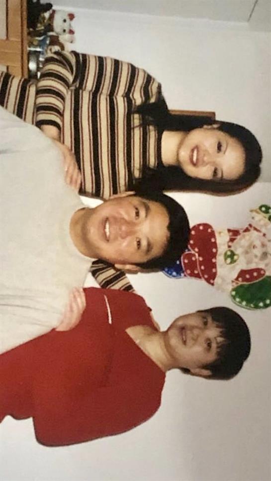 Three friends smile with festive decorations at a holiday gathering.