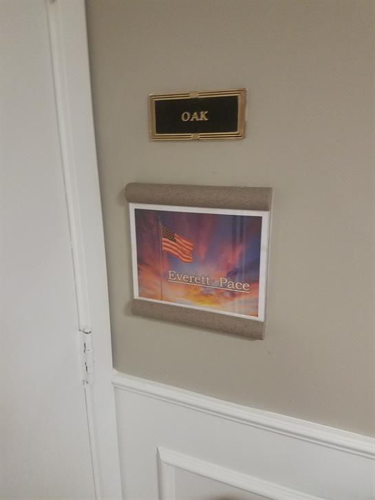 A room sign features the name OAK alongside colorful artwork and flags, brightening the corridor.