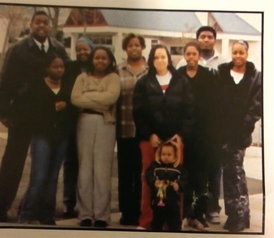 A group poses for a family portrait. They are outdoors.