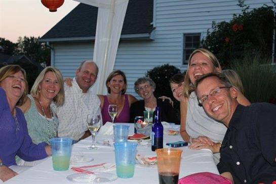A group of friends celebrates together outdoors, sharing drinks and smiles as the sun sets.