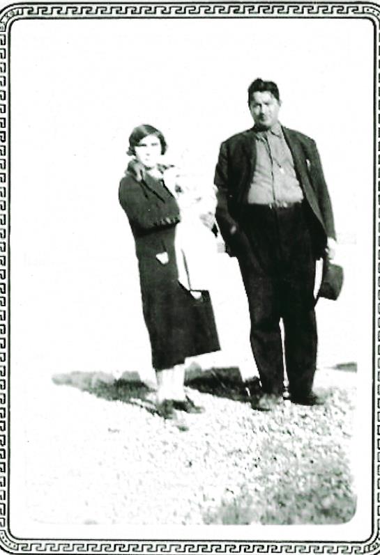 Couple poses outdoors in vintage clothes with a serene landscape behind them.