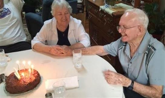 Two seniors share a joyful moment at a table, enjoying cake and warm conversation together.
