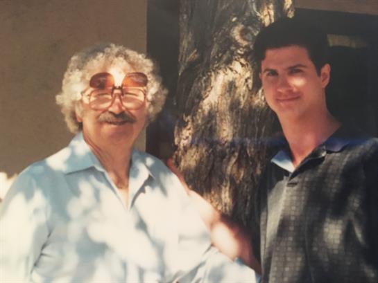 Two individuals share a friendly moment outdoors, surrounded by natural light and shadows.