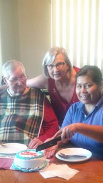 Three individuals interact warmly in a comfortable space, sharing smiles and connection.