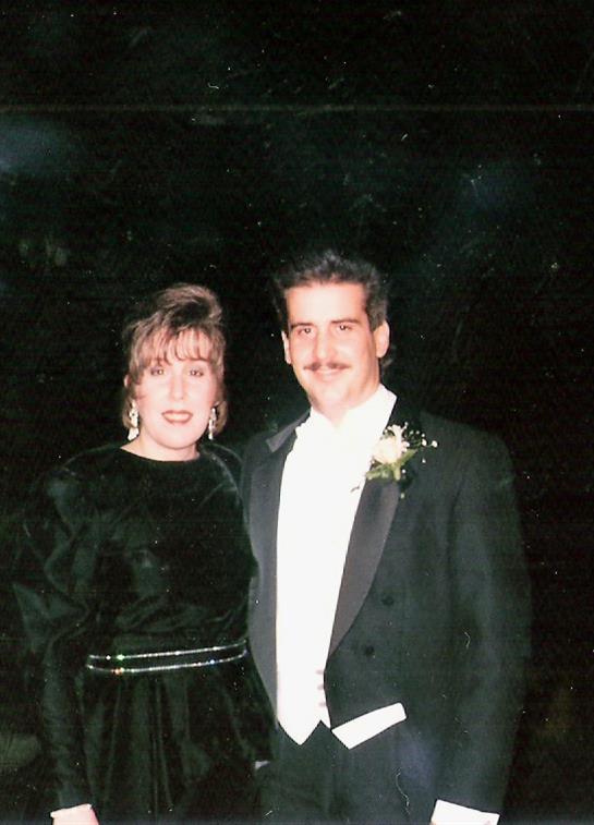 A couple in formal attire poses together at a black-tie event filled with joy and celebration.