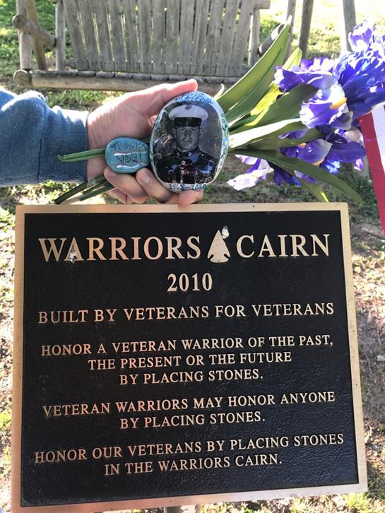Participants honor veterans at Warriors Cairn by placing stones in remembrance.