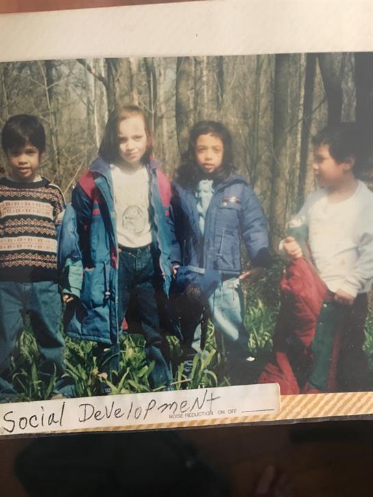 Four kids bundled up outdoors join a social development project in the woods.