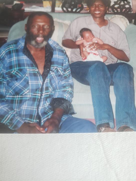 A loving family moment captured with a grandfather, mother, and baby together at home.