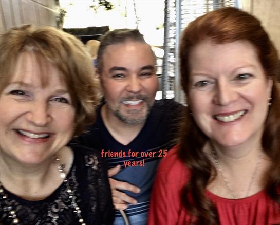 Three friends smile at a gathering, celebrating 25 years of friendship and memories.