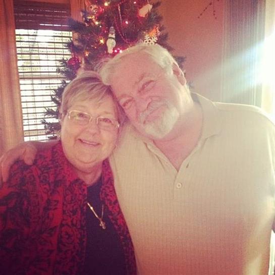 Two friends embrace and smile warmly together in a festive setting during a holiday celebration.
