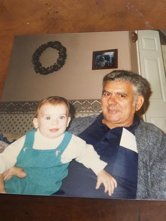A loving grandfather sits with his baby grandchild in a warm and inviting living room atmosphere.