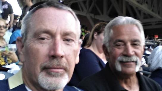 Two men share a moment in a lively setting, both smiling and enjoying their time together.