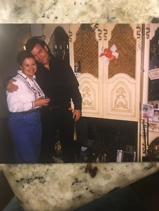 A couple shares a joyful moment in festive attire amid indoor decorations.