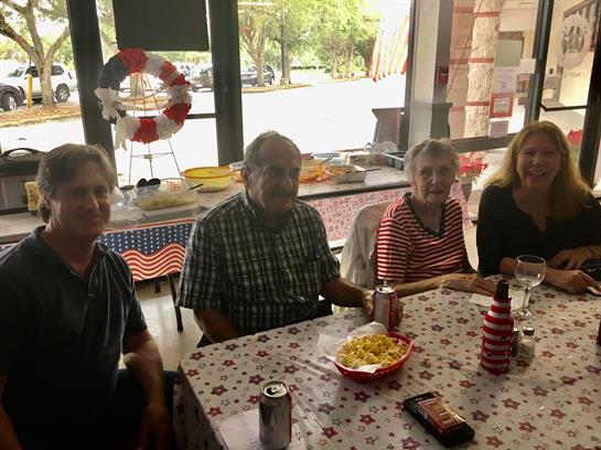 Four friends sit around a table, sharing snacks and beverages while enjoying each other's company.