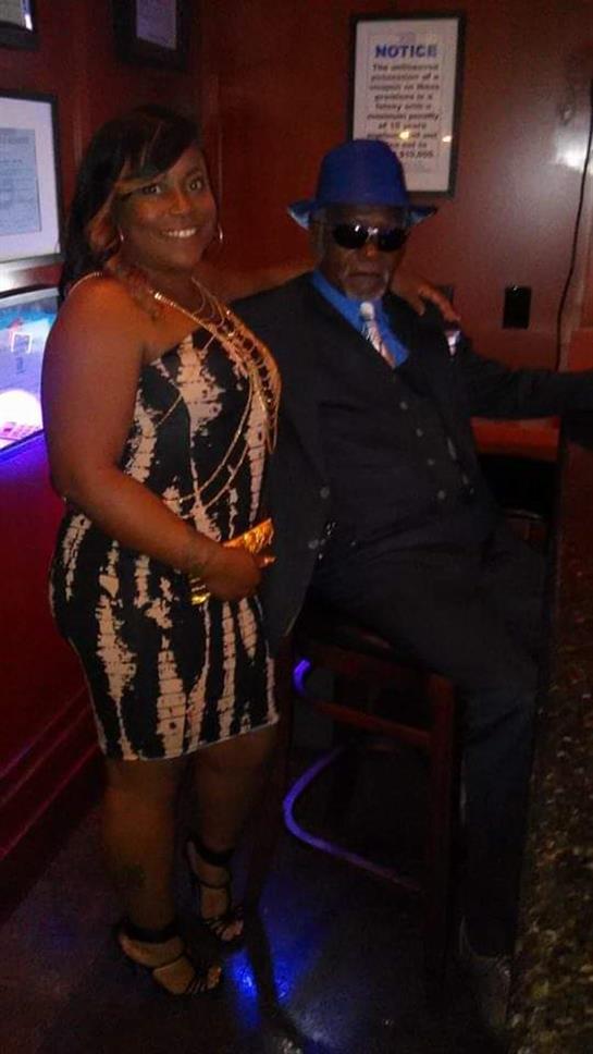 Stylishly dressed couple poses together in a lively lounge environment, enjoying the night.
