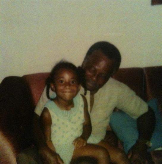 A joyful child sits on a grandparent's lap, both sharing smiles in a warm living room atmosphere.