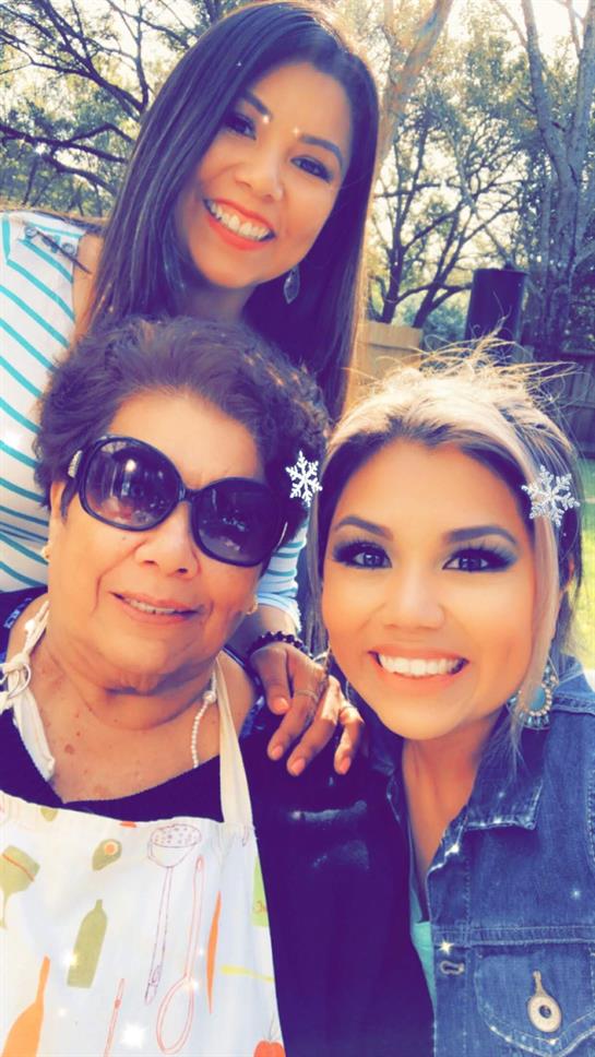 Three women gather in a sunny outdoor setting, sharing smiles and enjoying each other's company.