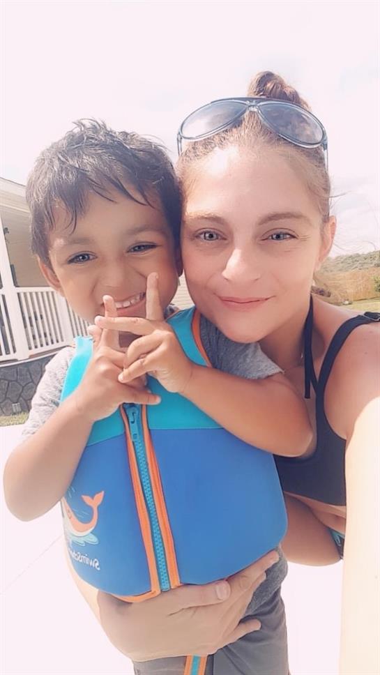 A child and adult enjoy playful interaction by the beach, capturing a moment of happiness together.