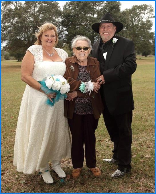 Couple celebrates their wedding day with their grandmother in a beautiful outdoor setting.