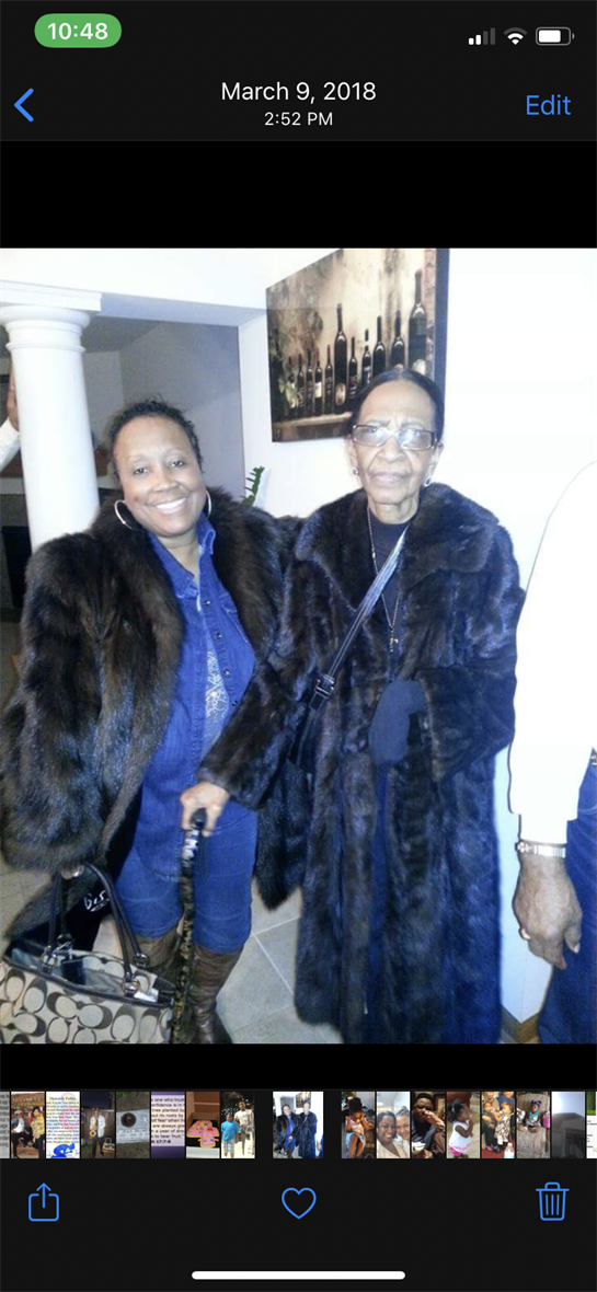 Two women smile while posing together in elegant fur coats at a gathering.