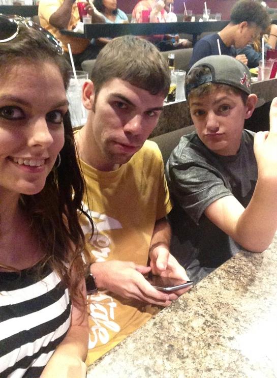Three friends smile and pose for a selfie while enjoying time at a restaurant during dinner.