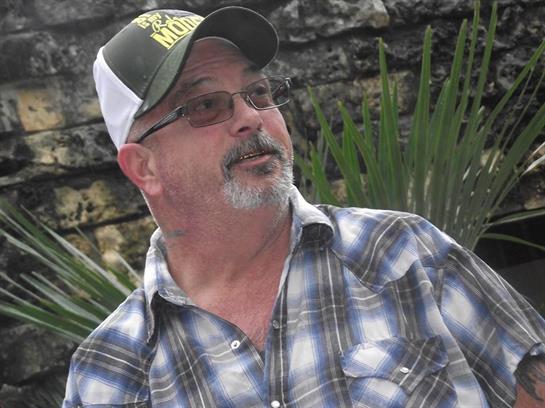 Casual gathering occurs as a man engages with others surrounded by lush greenery.